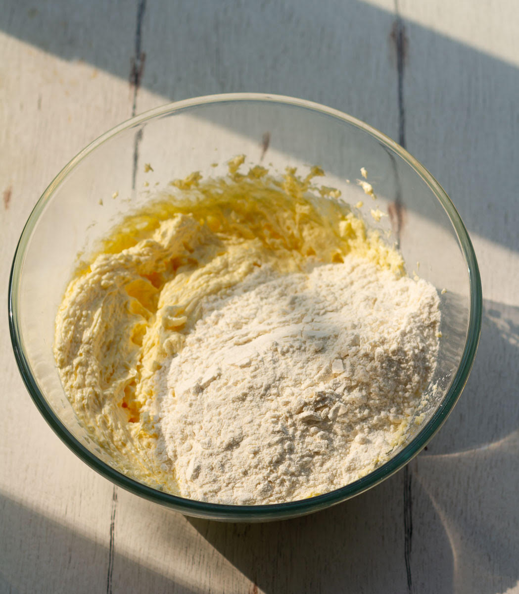 Flour on top of butter mixture in a mixing bowl.