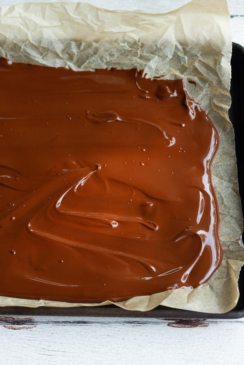Melted chocolate spread on a parchment lined tray.