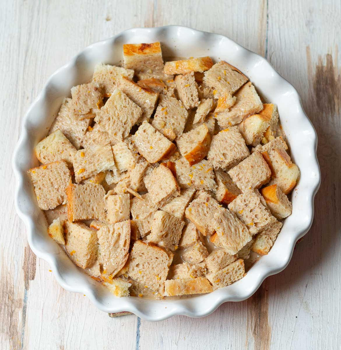 Bread cubes soaking in milk and egg mixture in a baking dish.