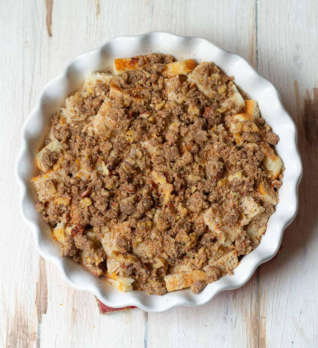 Crumble topping on top of cubed bread in a baking dish.
