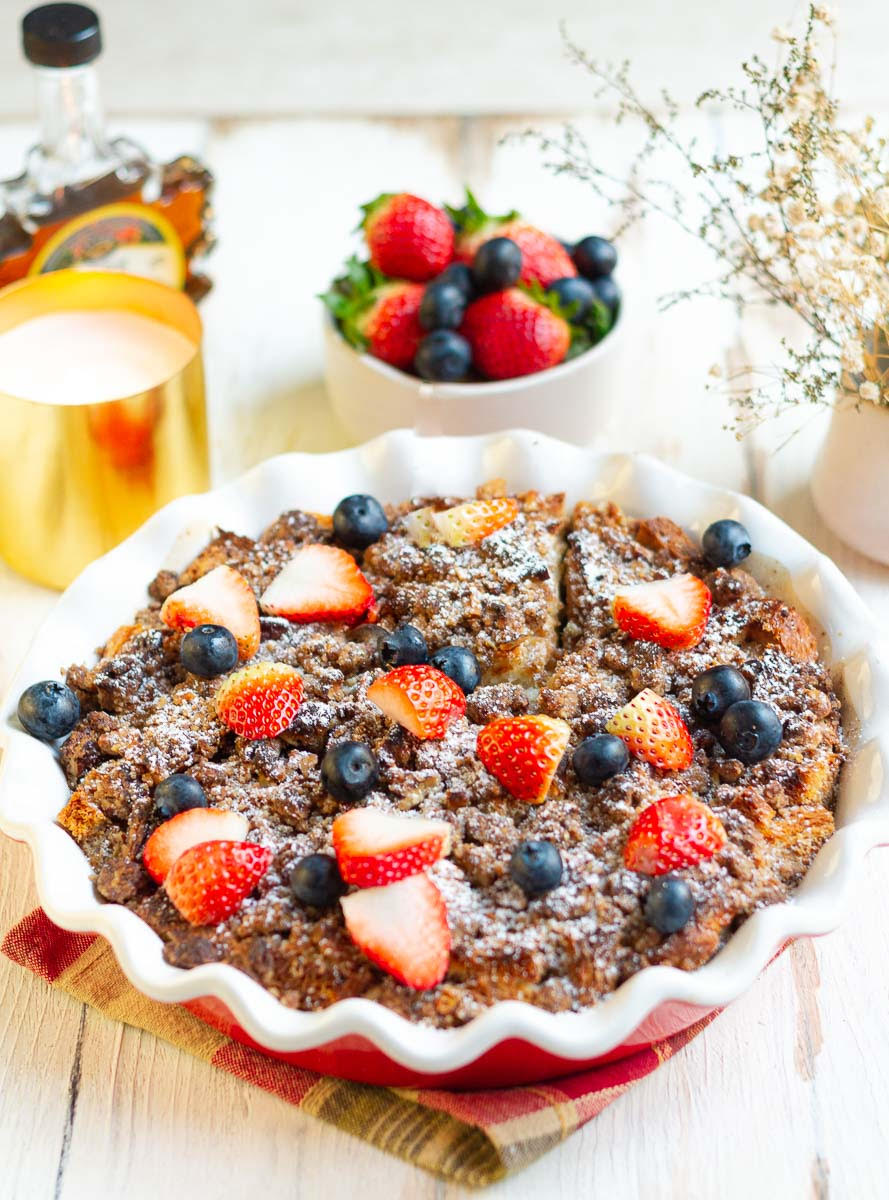 French Toast Casserole topped with berries with ingredients around.
