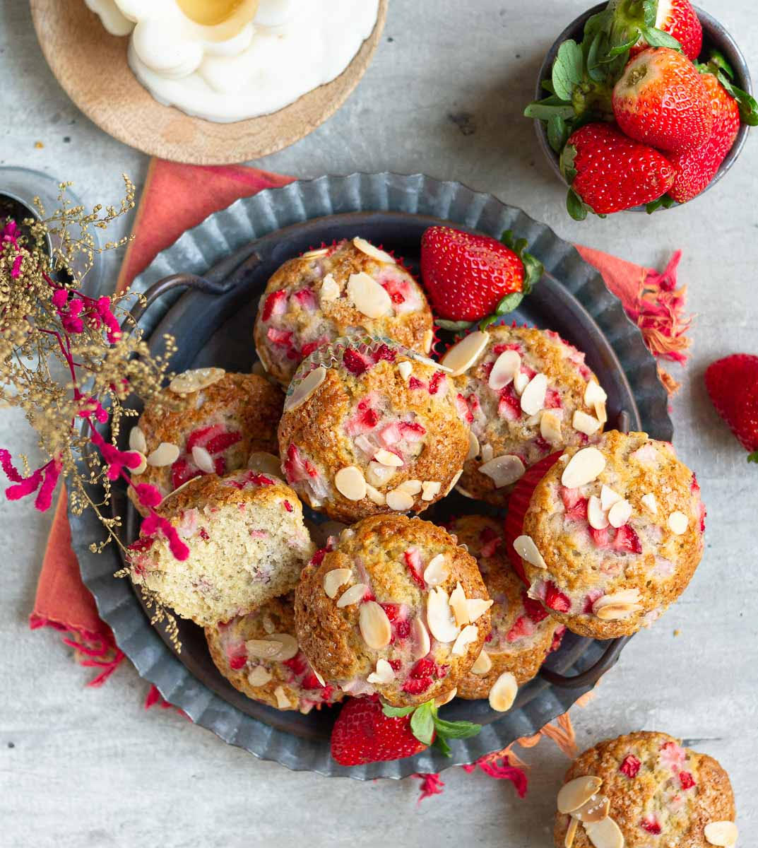 Strawberry banana muffins on a metal tray with one half of a muffin to show the texture.