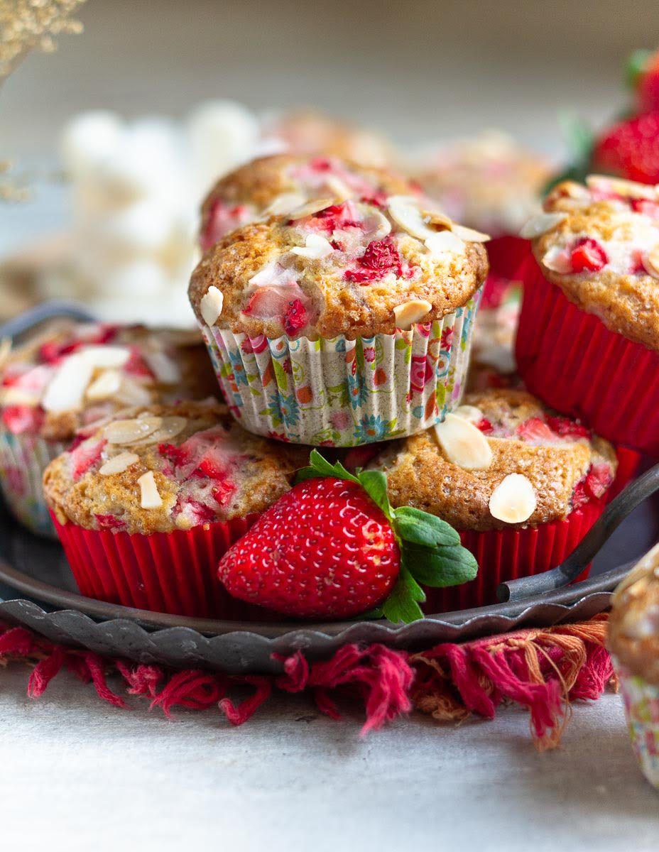 Muffins stacked on a metal tray with a fresh strawberry.