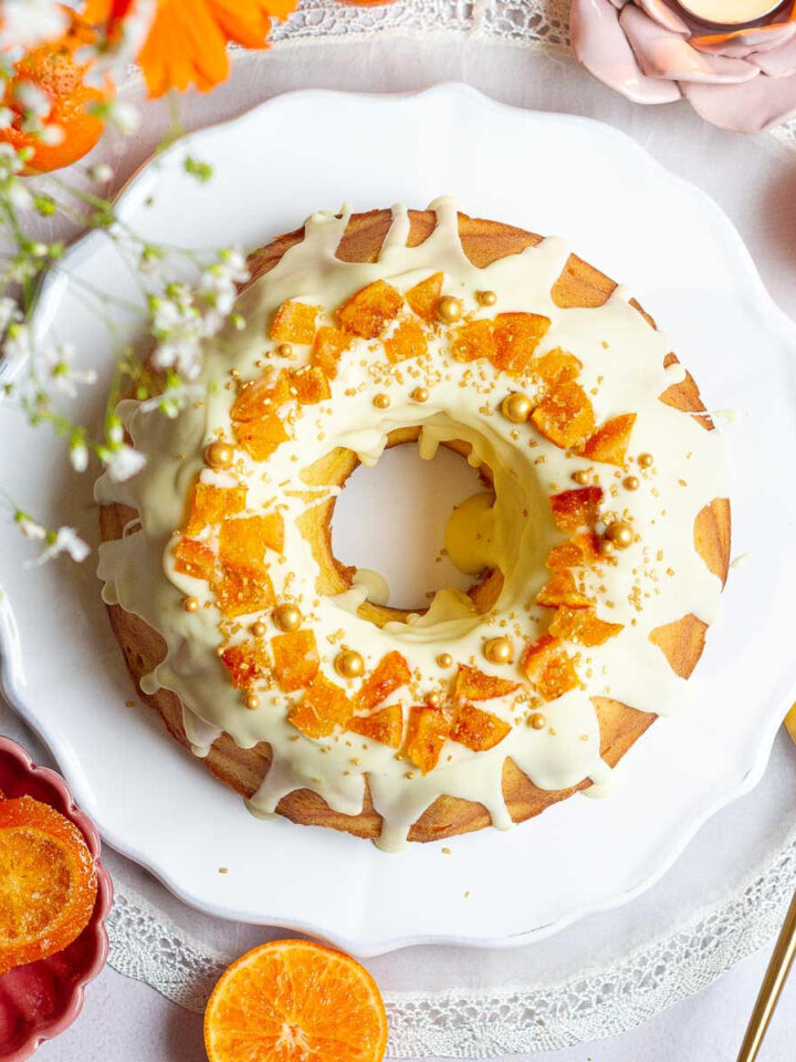 Orange bundt cake on a white serving platter.