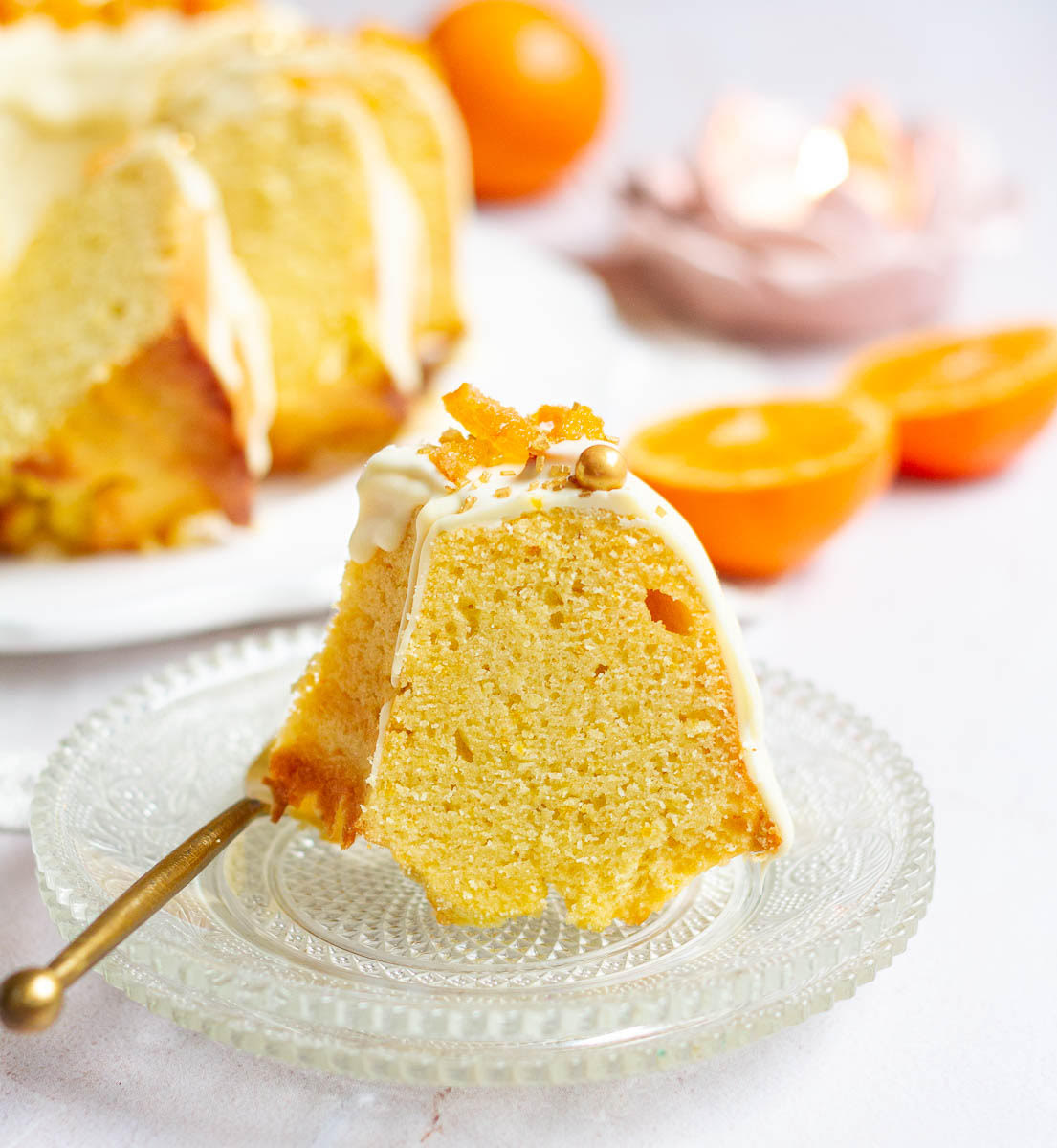 A slice of orange cake on a small plate with a fork.