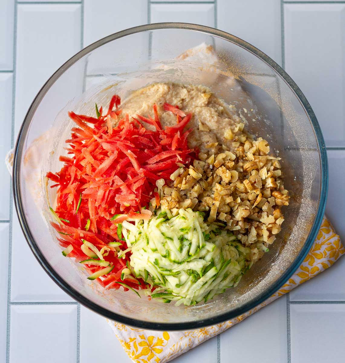Bread batter with shredded carrots, zucchini and walnuts in a mixing bowl.