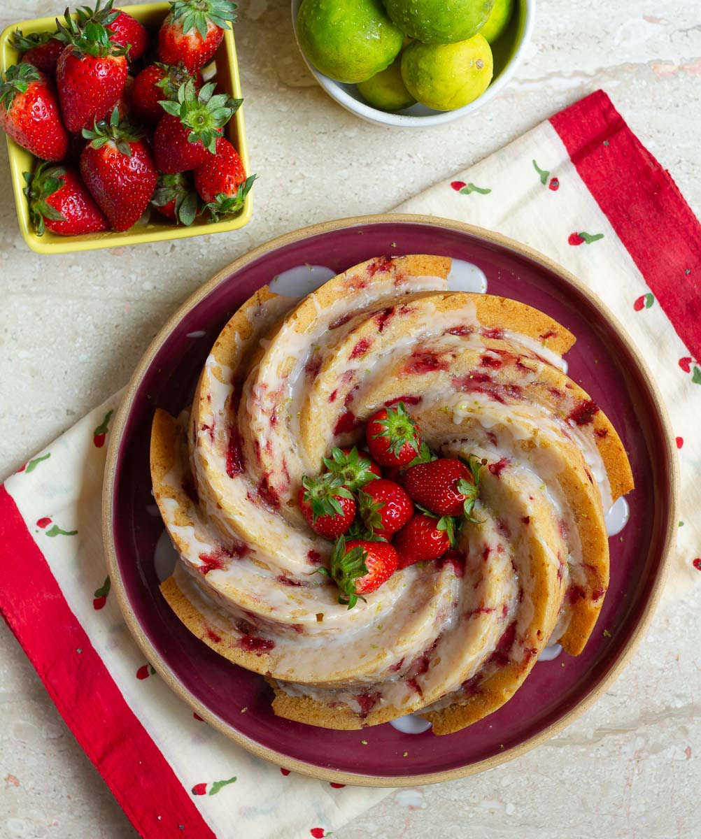 strawberry lemon bundt cake on a red serving plate with ingredients on the side.