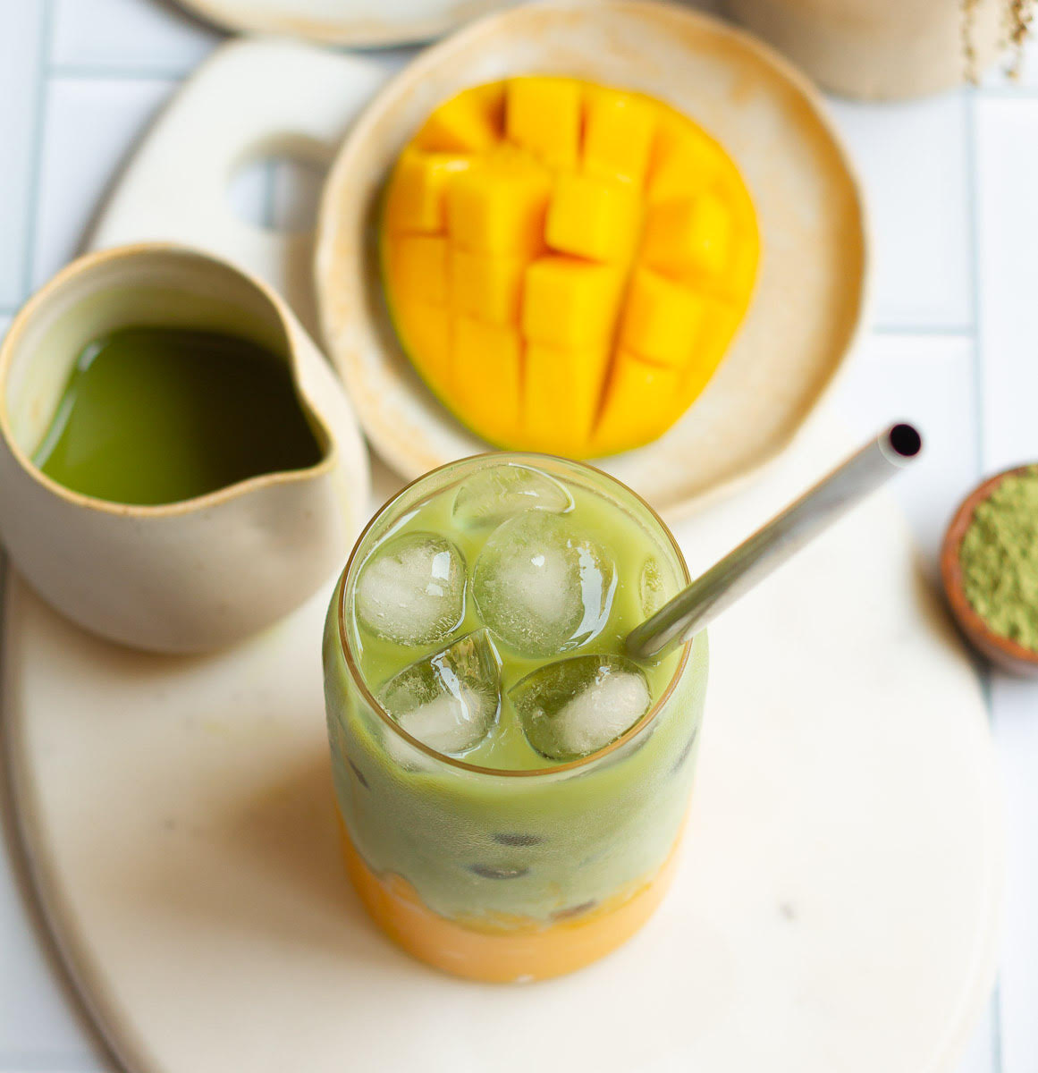 Mango Matcha Latte in a glass with a steel straw.