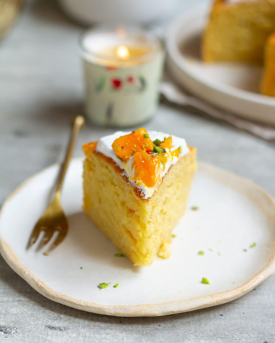 A slice of mango cake on a plate with a fork.