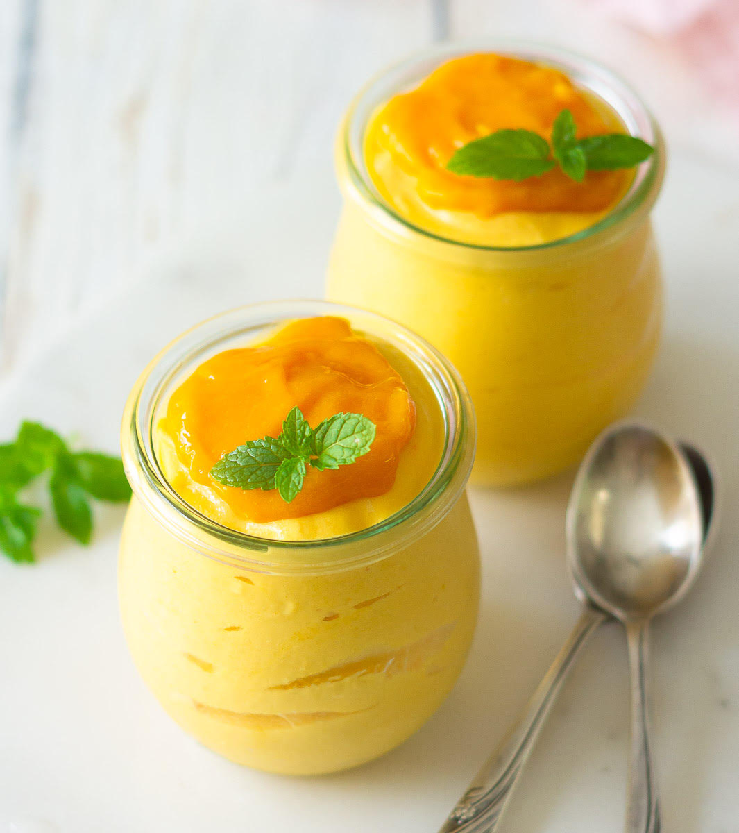 Mango Mousse in 2 jars with spoons on the side.