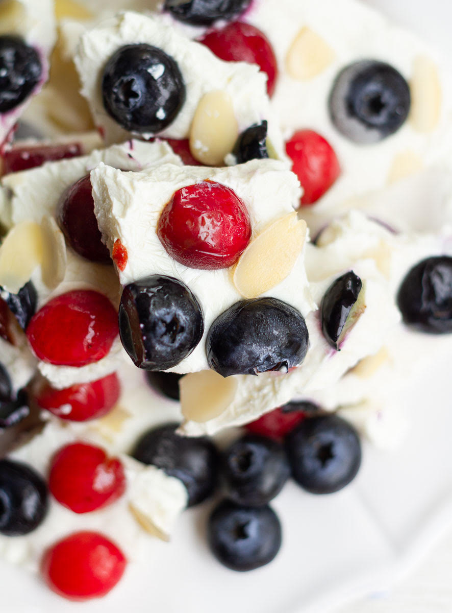 Yogurt bark with blueberries, cherries, and almonds stacked on a plate.