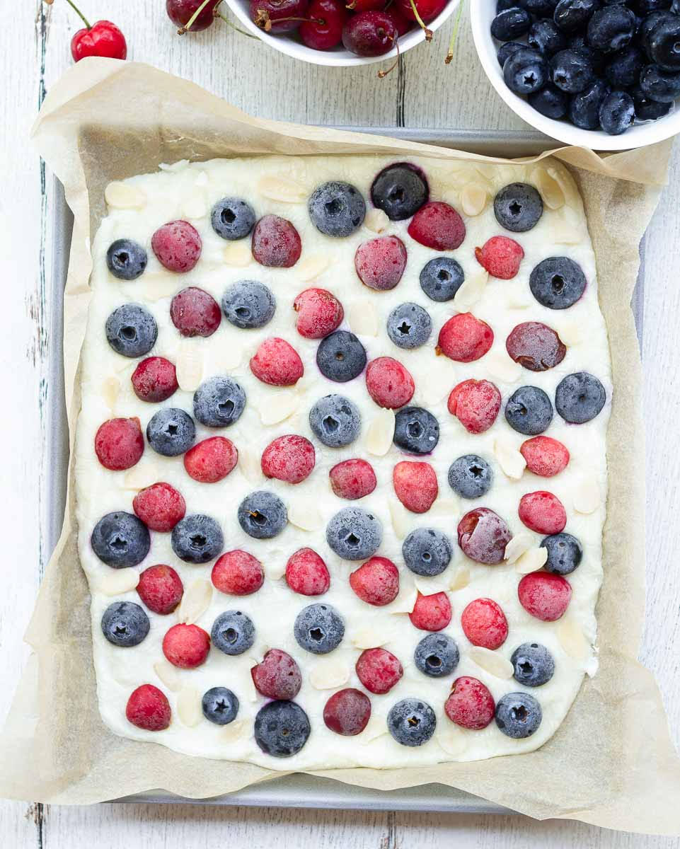 Frozen yogurt bark with cherries, blueberries, and almonds on parchment paper.