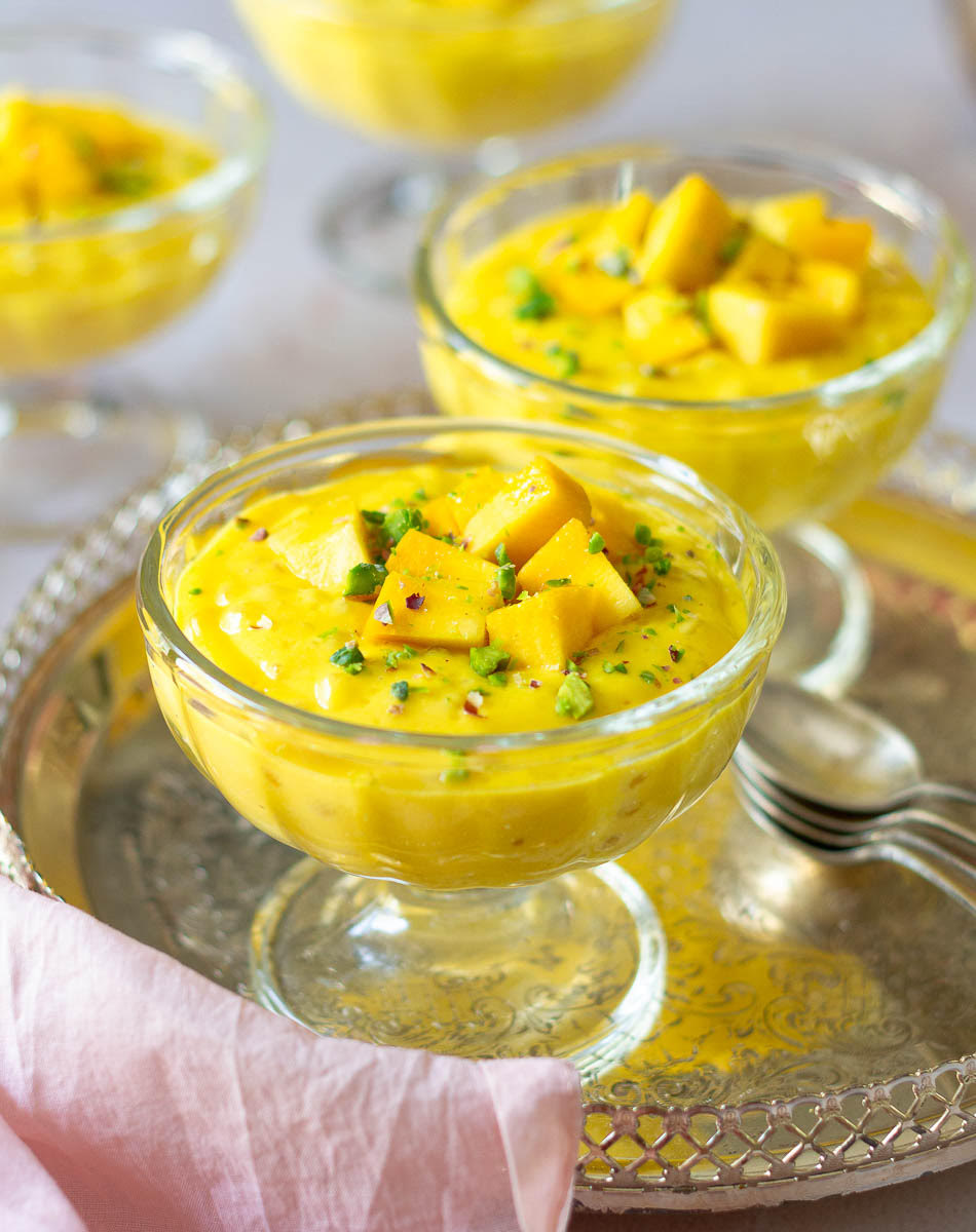 Mango sago dessert in dessert glasses with spoons on the side.