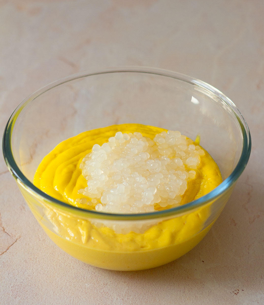 Cooked sago on top of the mango mixture in a bowl.