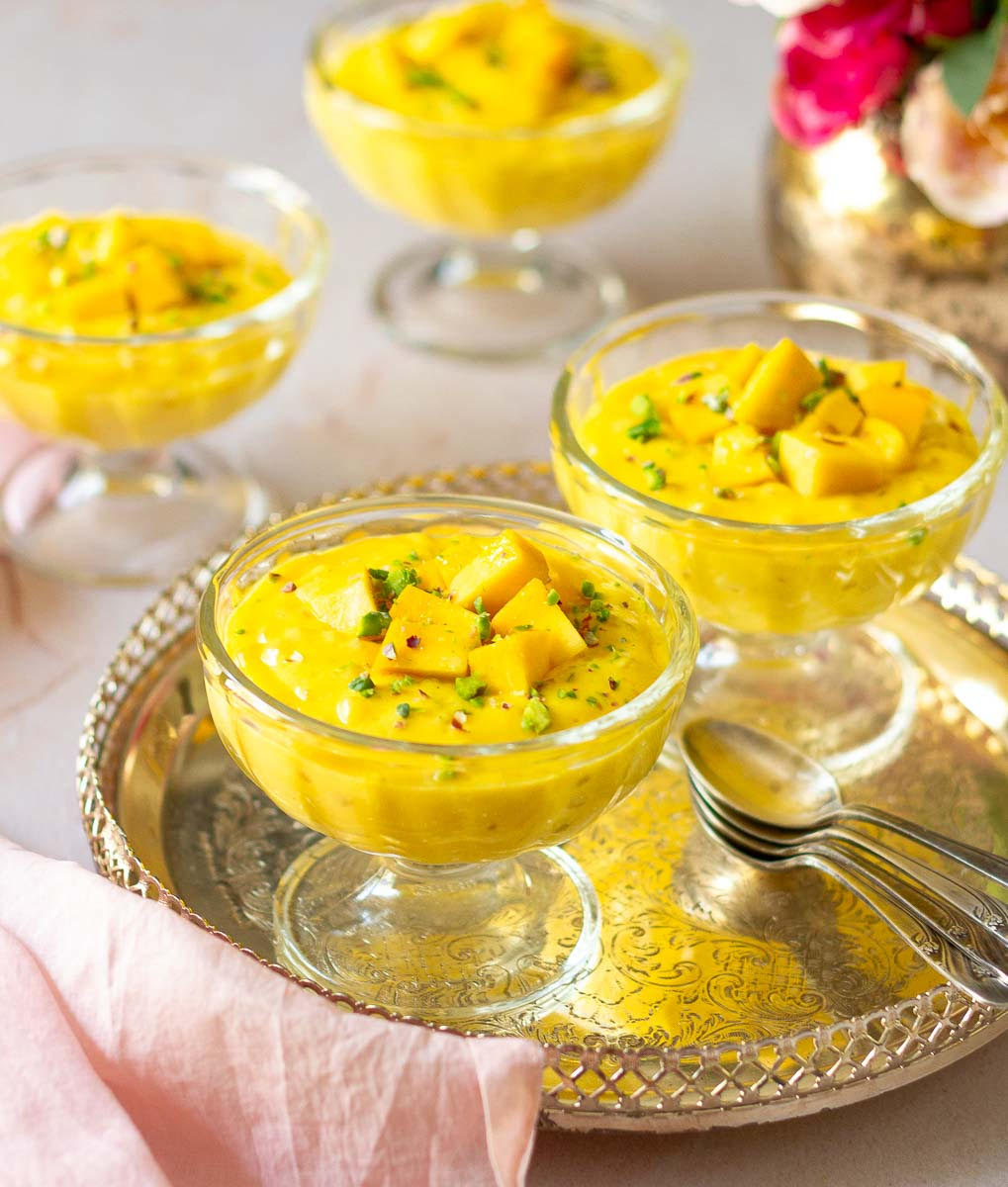 Mango sago pudding in 4 dessert cups on a tray.