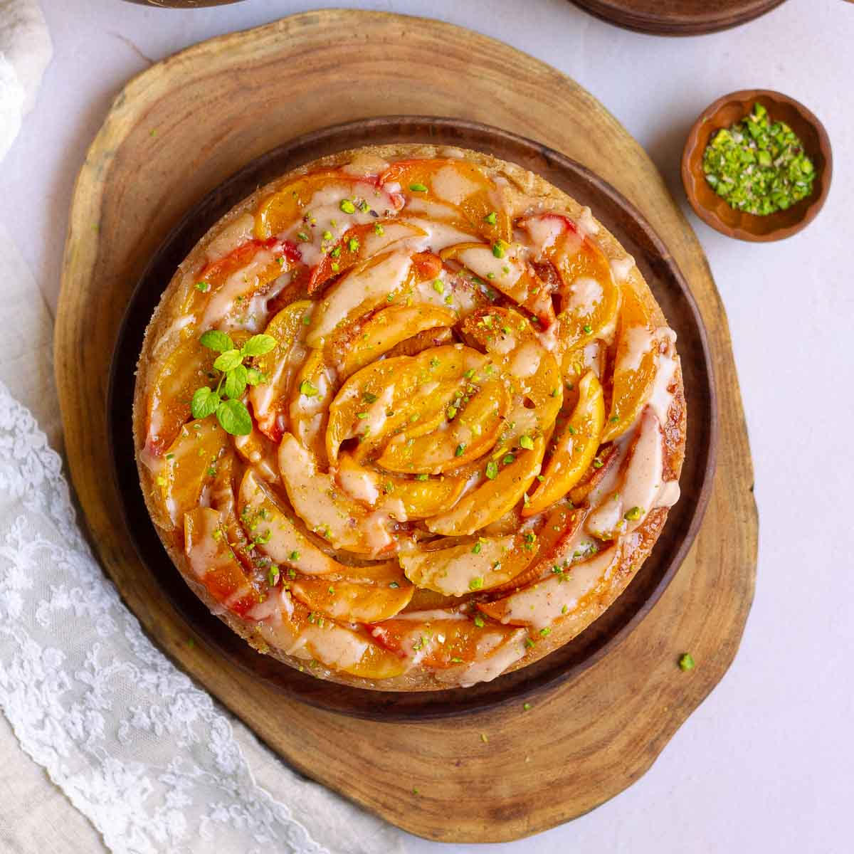 Peach Cobbler Cake with cinnamon glaze on a wooden platter.