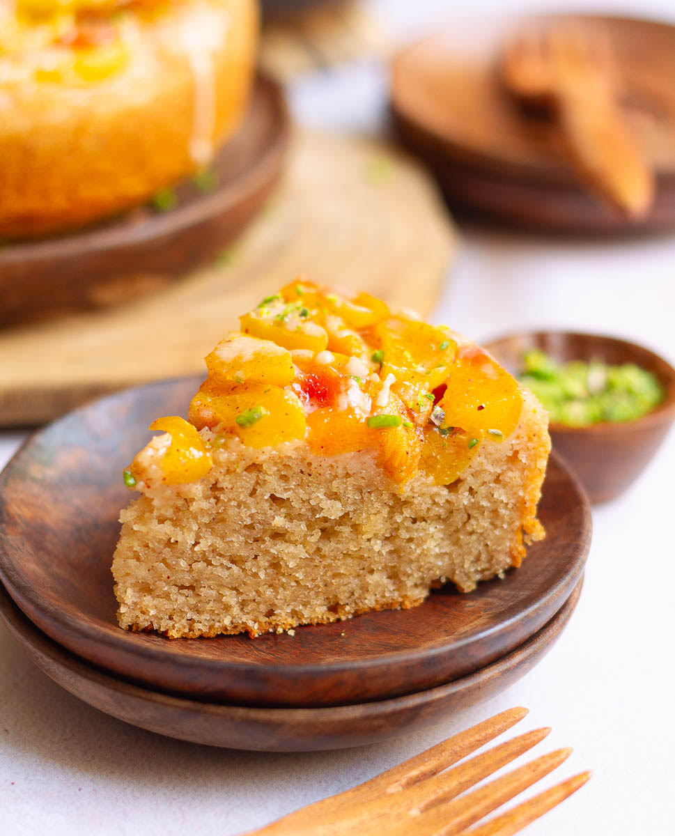 A slice of Peach Cobbler Cake on wooden plate.