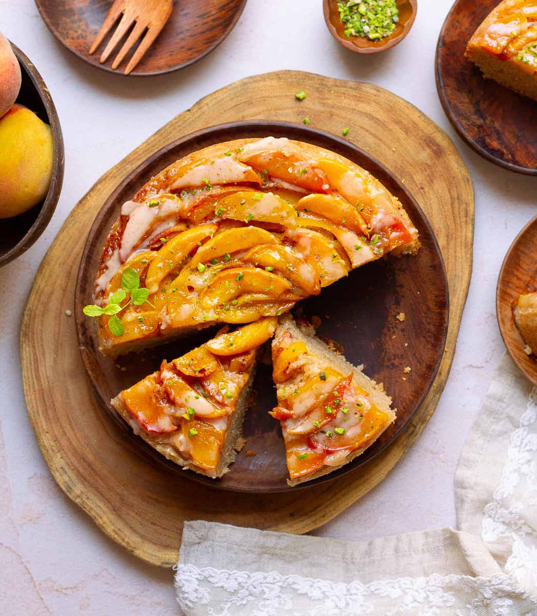 Sliced peach cake on a wooden platter.