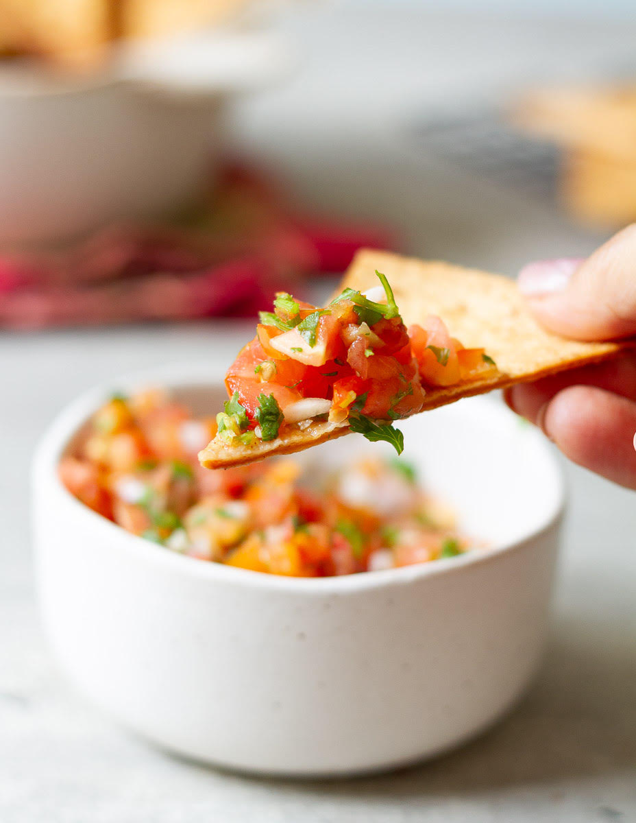 one air fried tortilla chip with scooped up tomato salsa.