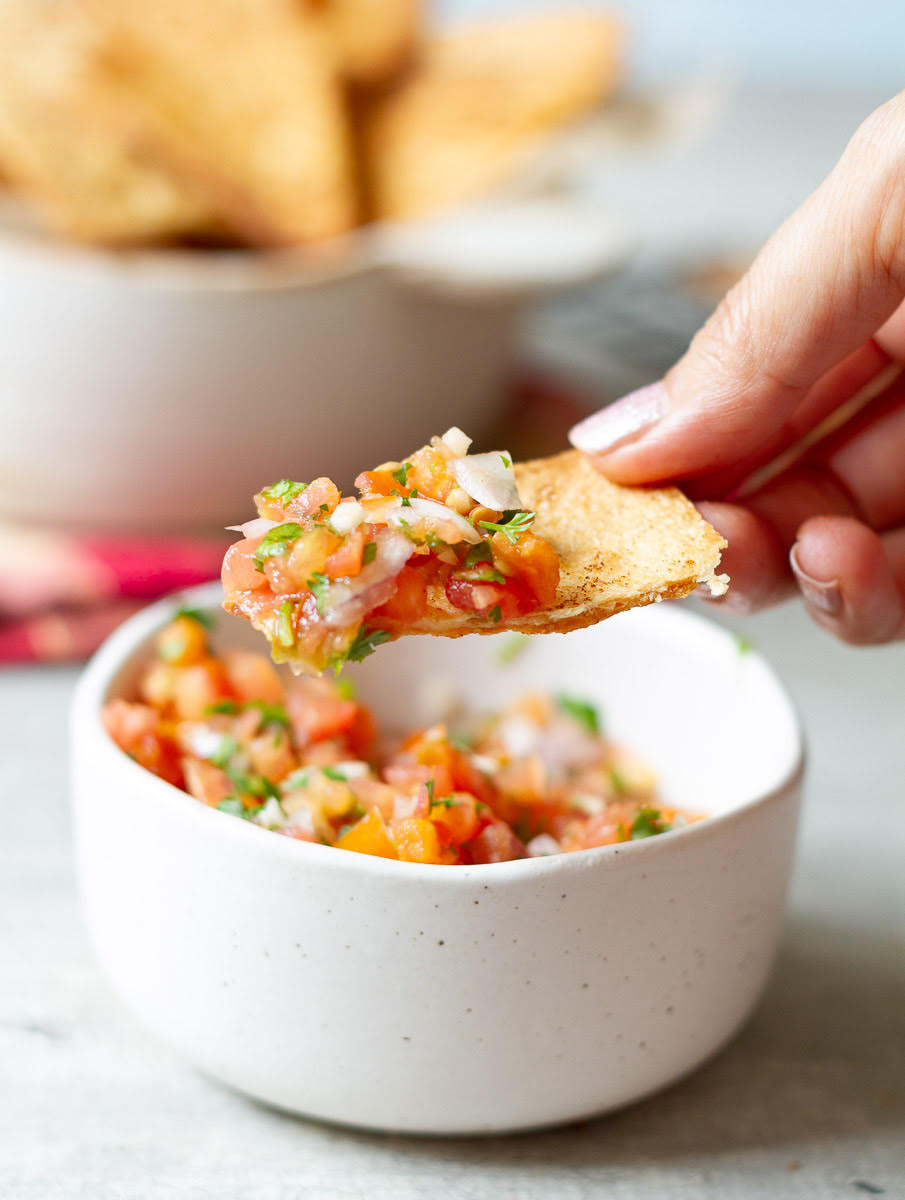 bite of tortilla chip with tomato salsa.