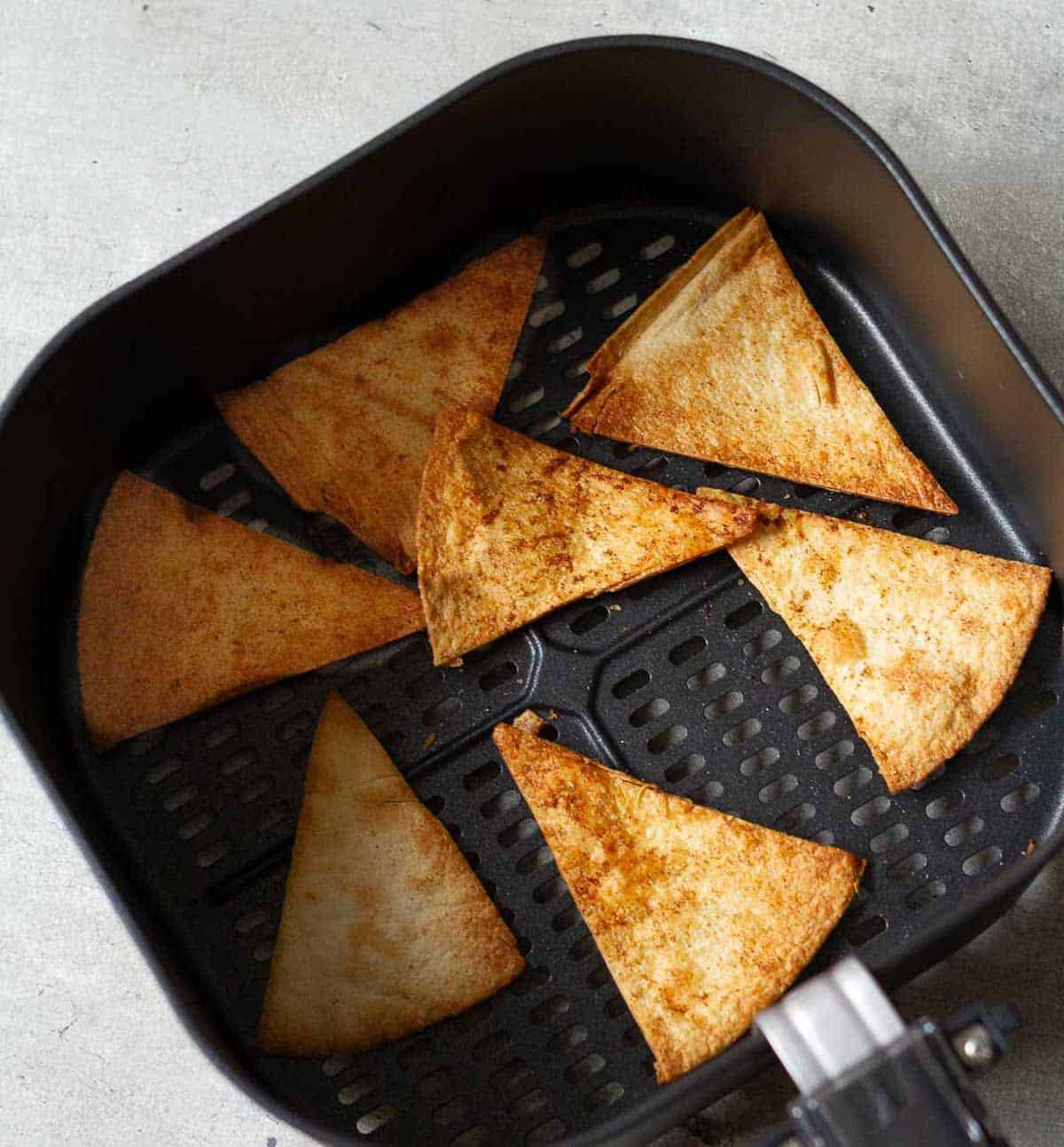 Golden and crunchy tortilla chips in the air fryer basket.