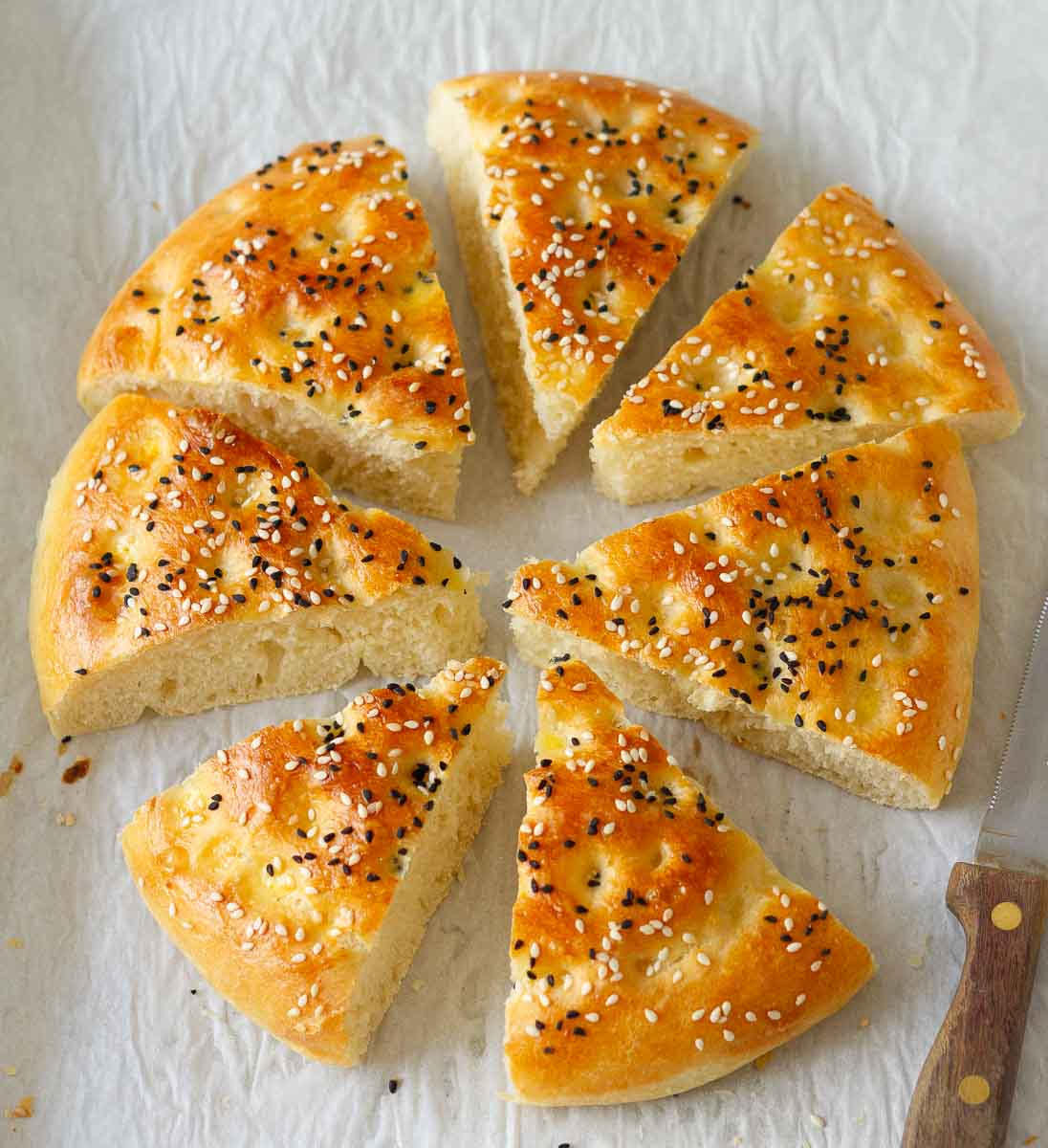 Turkish flatbread cut into wedges on a parchment paper.