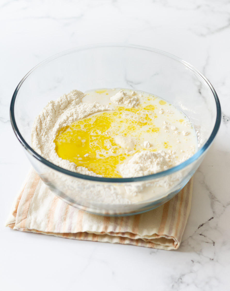 Milk, oil, flour, and yeast in a mixing bowl.