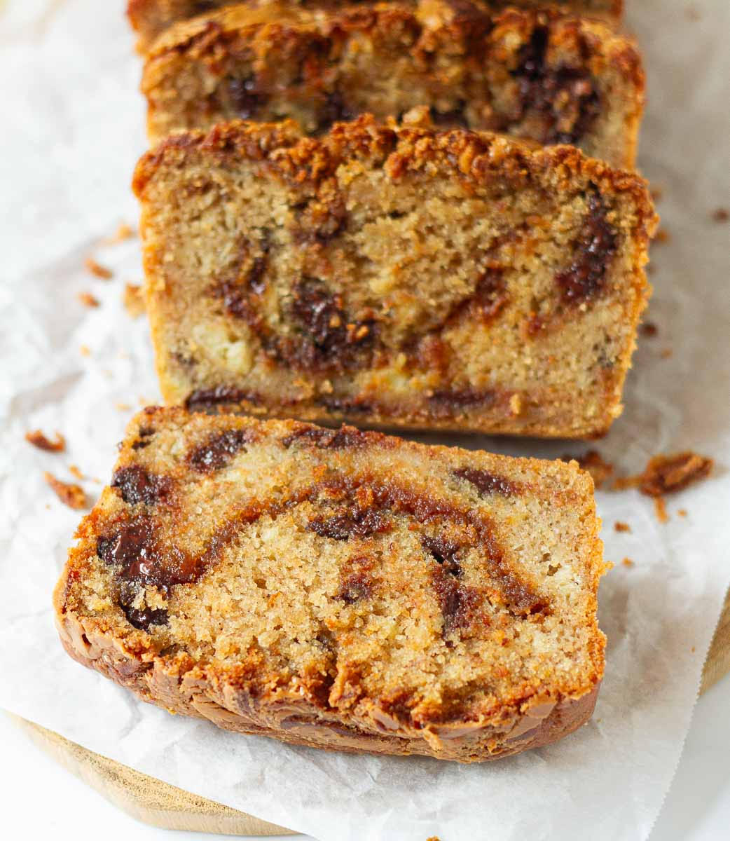 Sliced banana bread with biscoff swirls on parchment paper.
