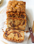 Sliced banana bread with biscoff with a knife on parchment paper.