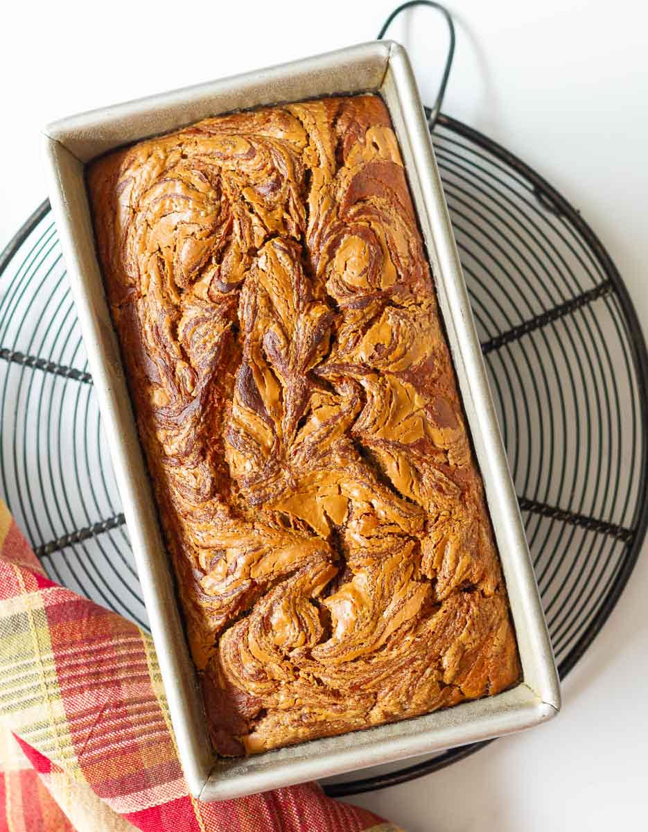 Baked Biscoff banana bread in a loaf tin on a wire rack.