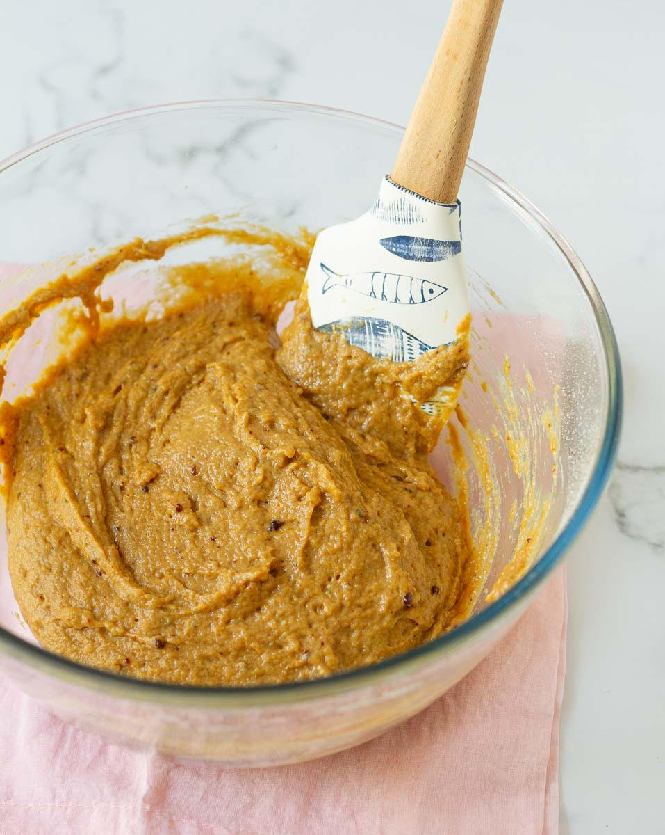 almond cardamom cake batter in a glass bowl with a spatula.