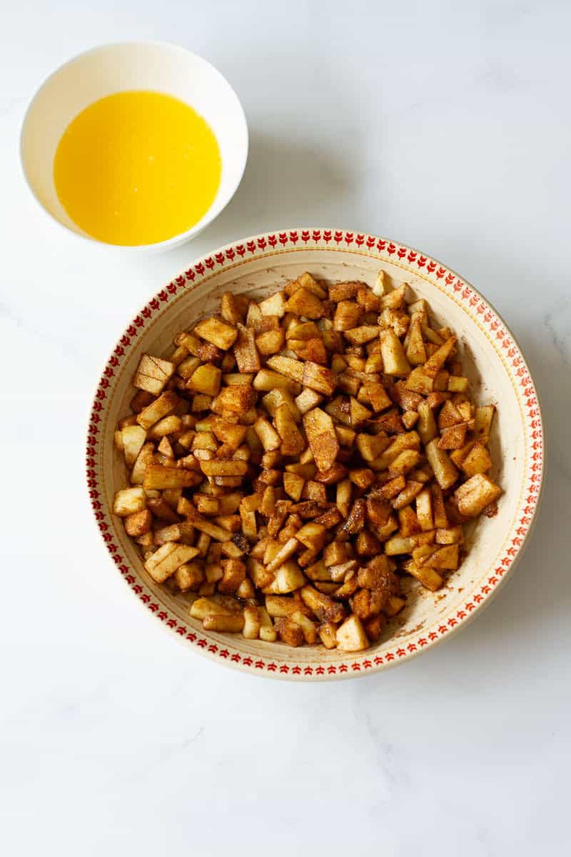 apples mixed with brown sugar and cinnamon powder and melted butter in a small bowl.