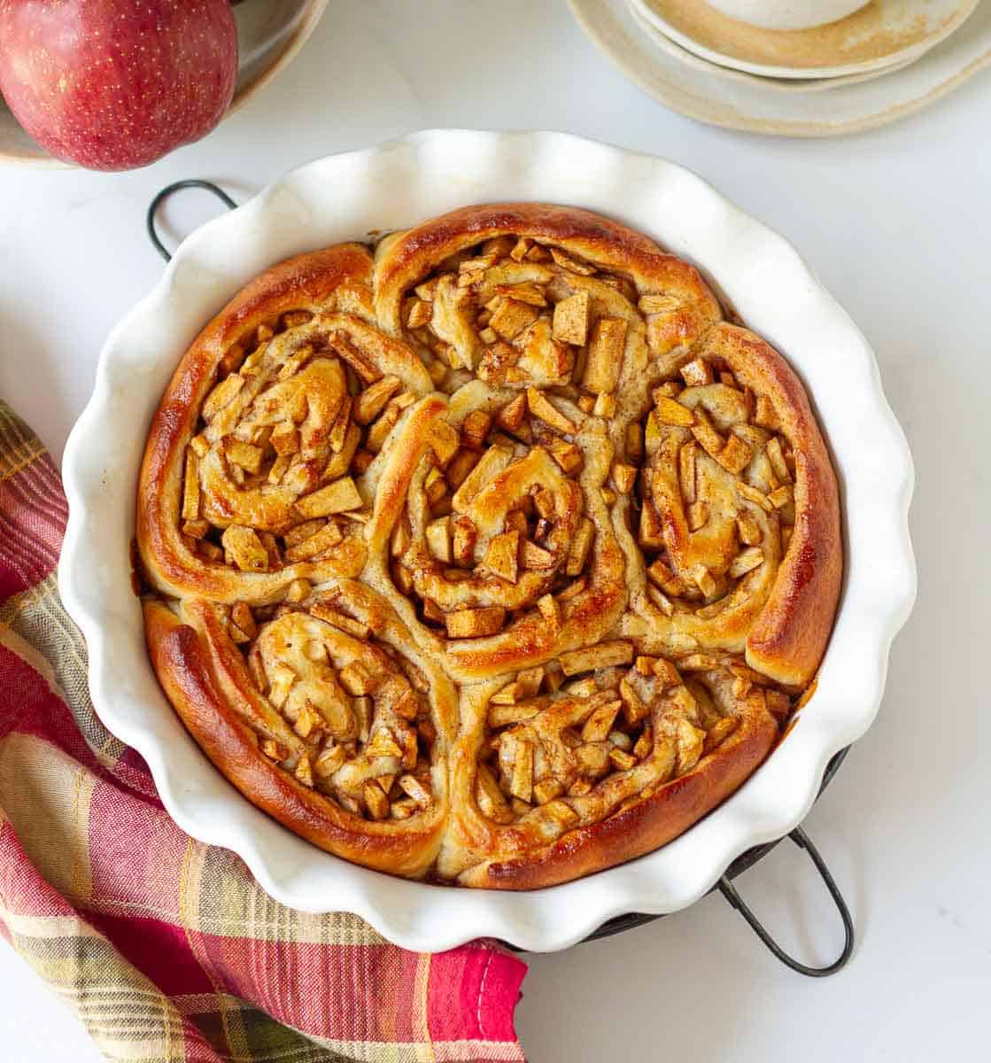 Baked apple pie cinnamon rolls in a round baking pan.