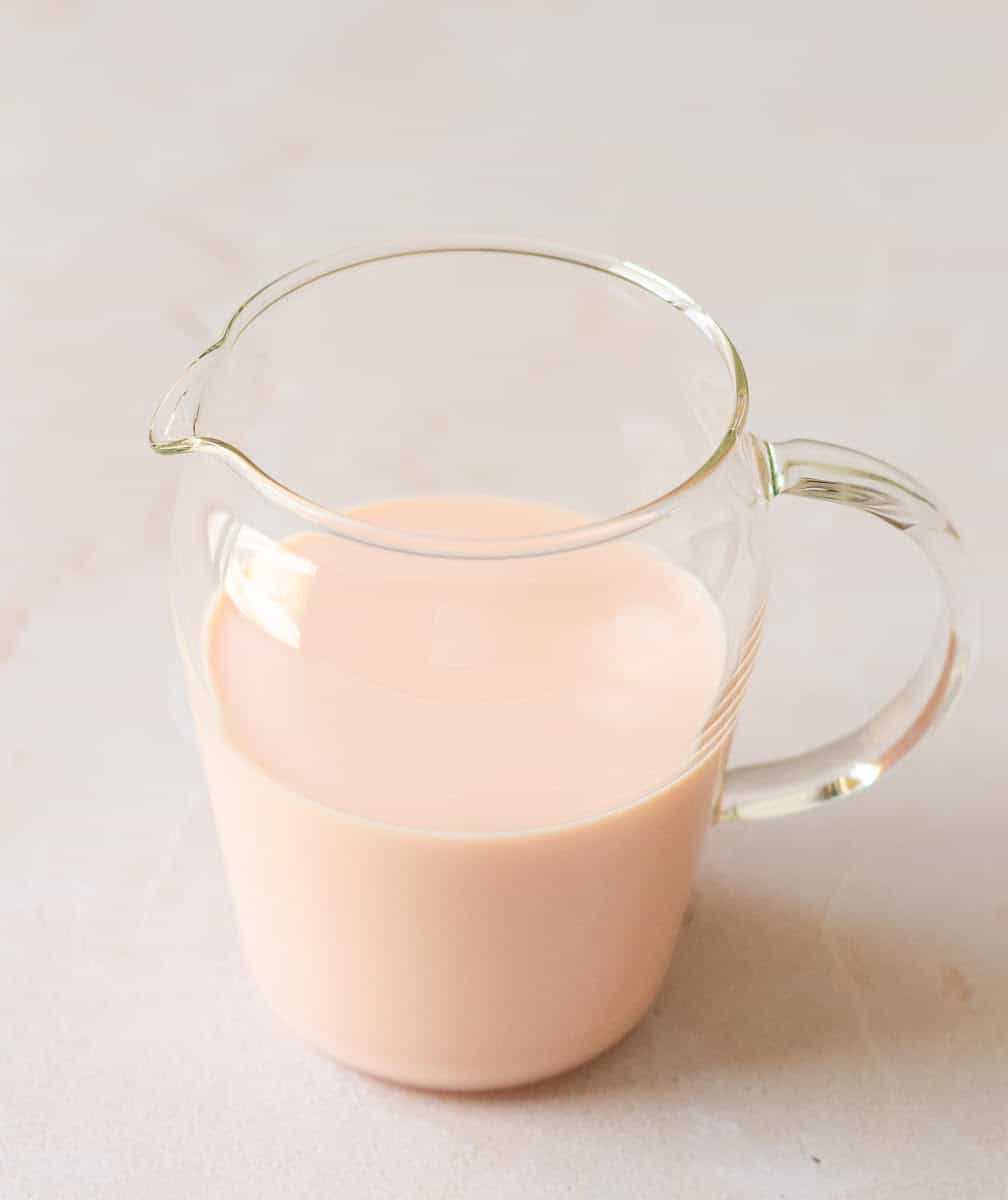 Rose milk syrup in a glass pitcher.