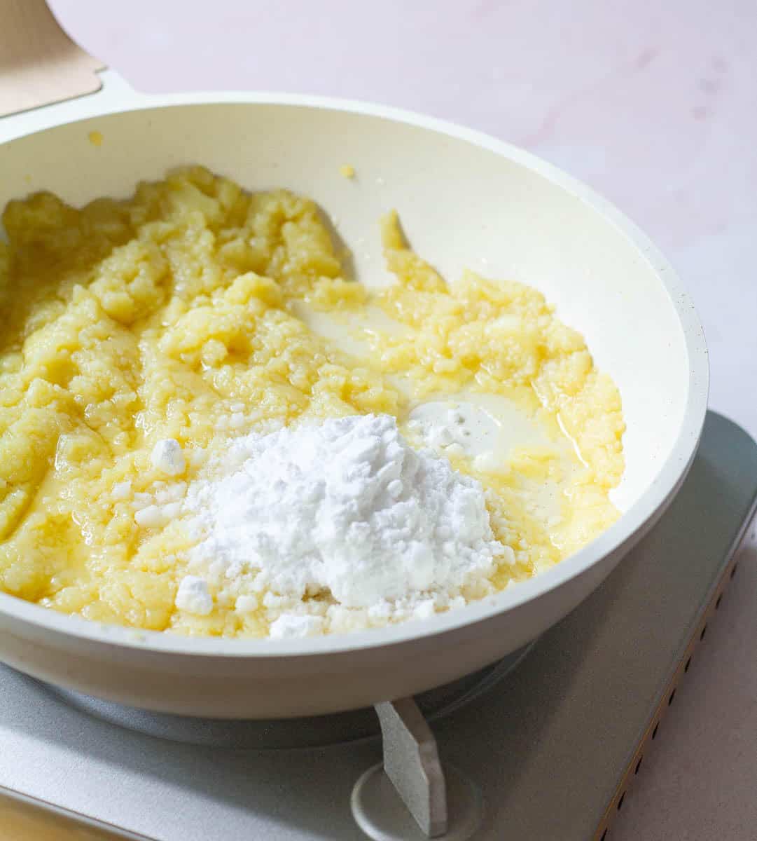 powdered sugar and melted khoya in a pan