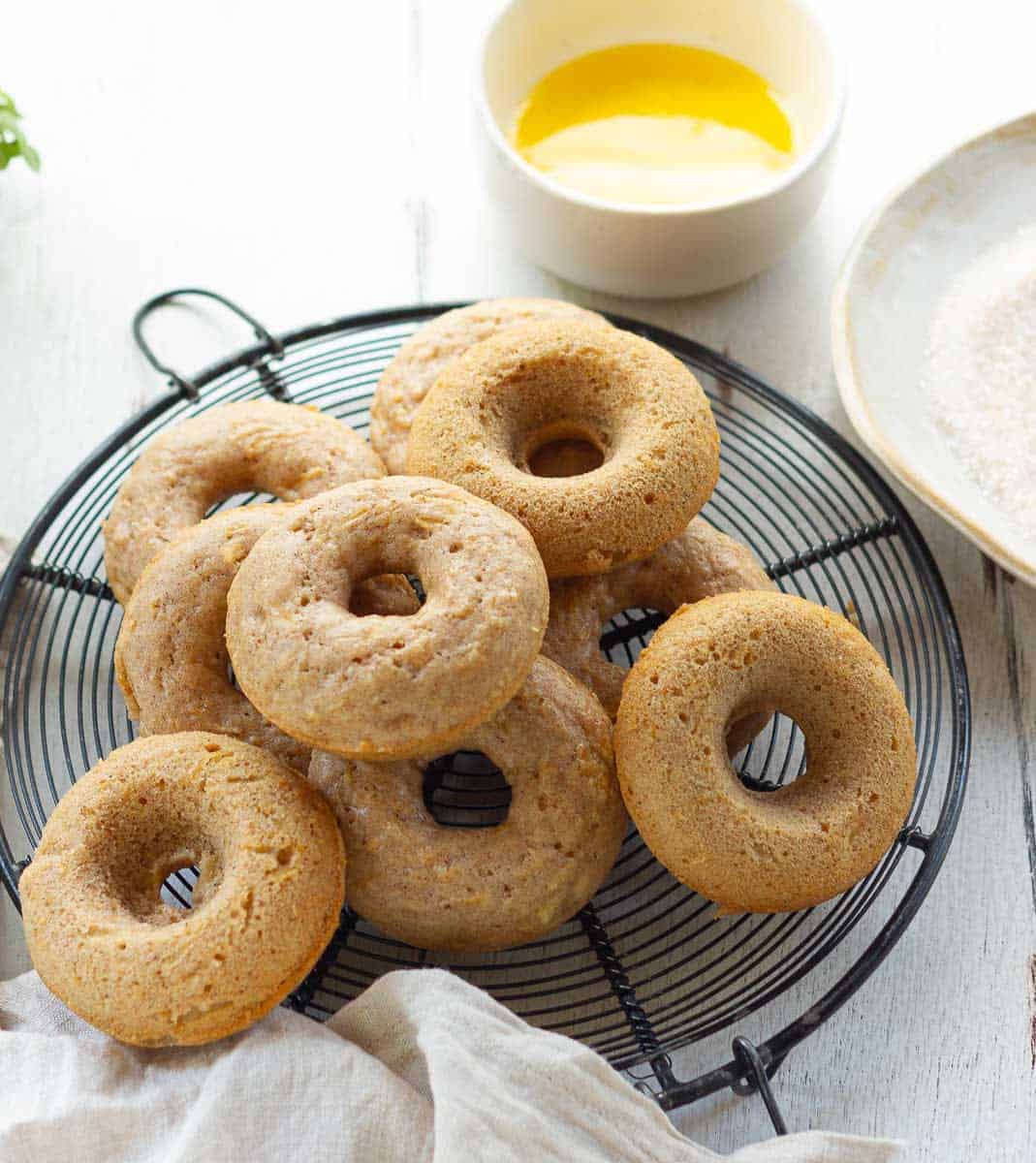 Baked apple donuts on a trivet with melted butter and cinnamon sugar.