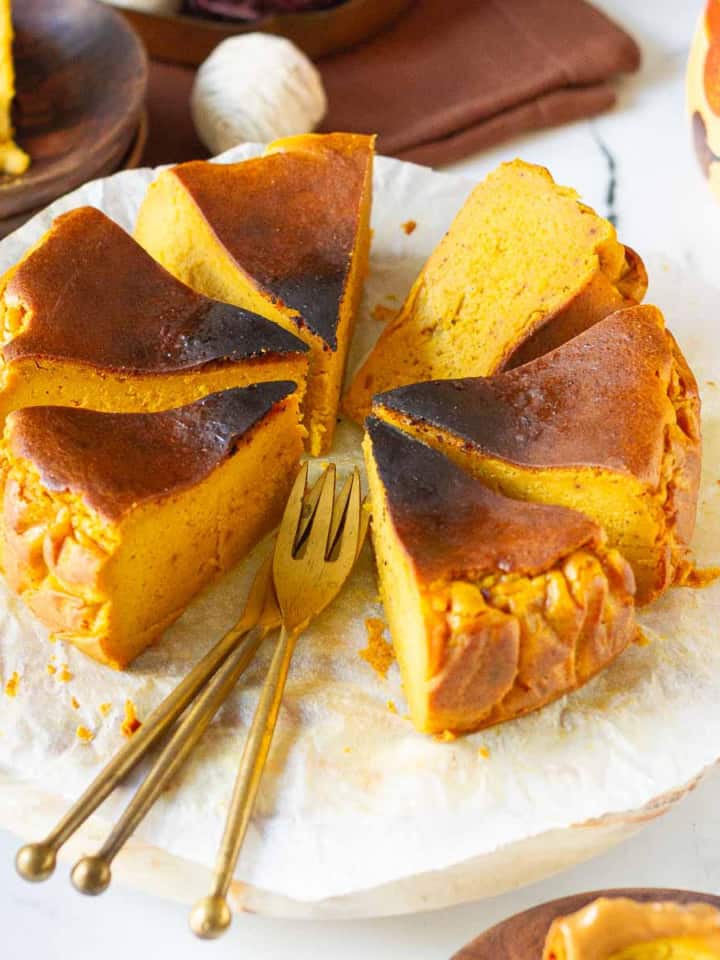 Sliced pumpkin cheesecake on parchment paper with 2 forks.