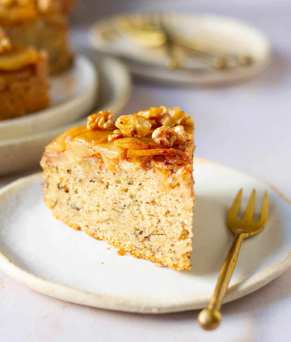 A slice of apple cake on a plate with a fork.