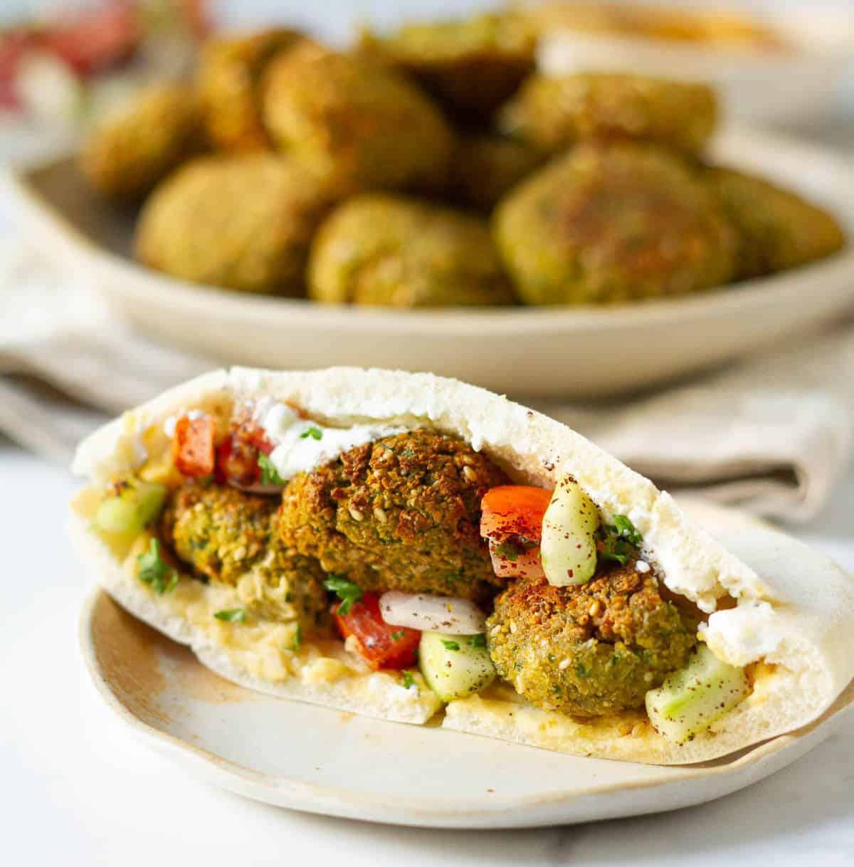 Filled pita pocket with falafel and salad on a plate.
