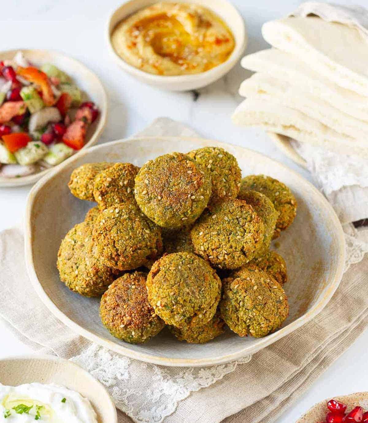 Falafels in a plate with ingredients in the background.