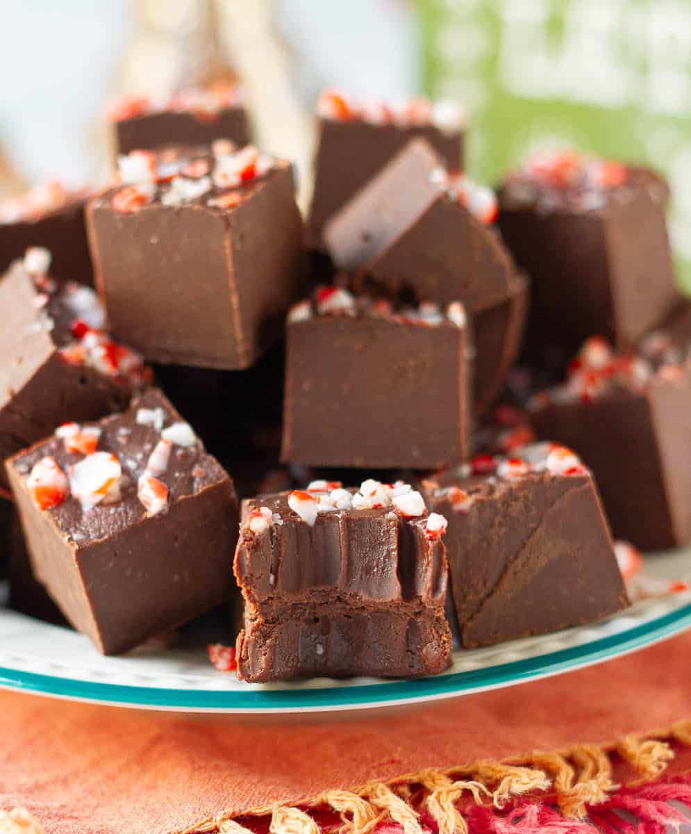 Chocolate fudge with crushed candy cane in a plate with one half eaten piece.