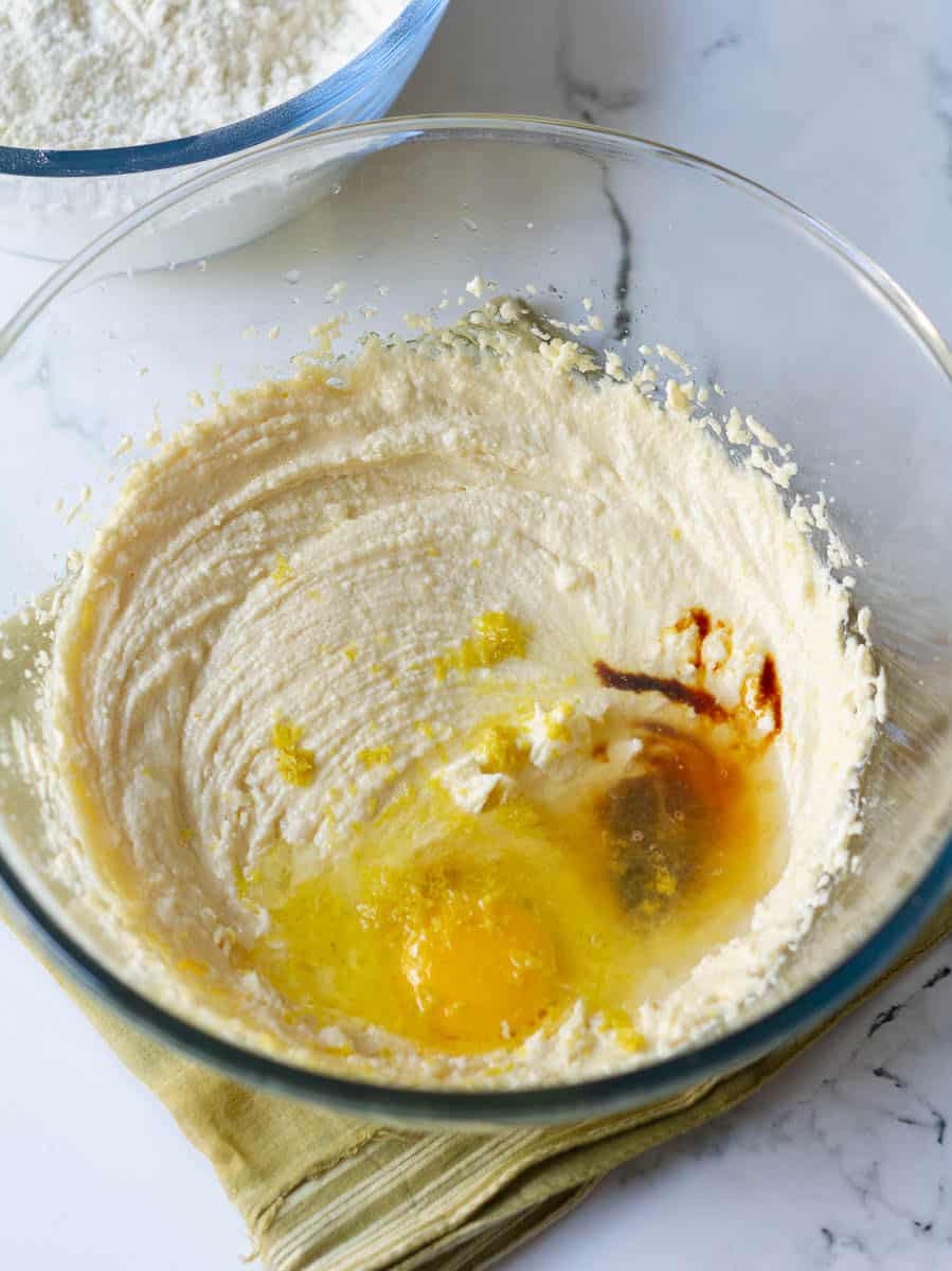 Add eggs, vanilla extract, lemon zest, lemon juice to a bowl of creamed butter and sugar.