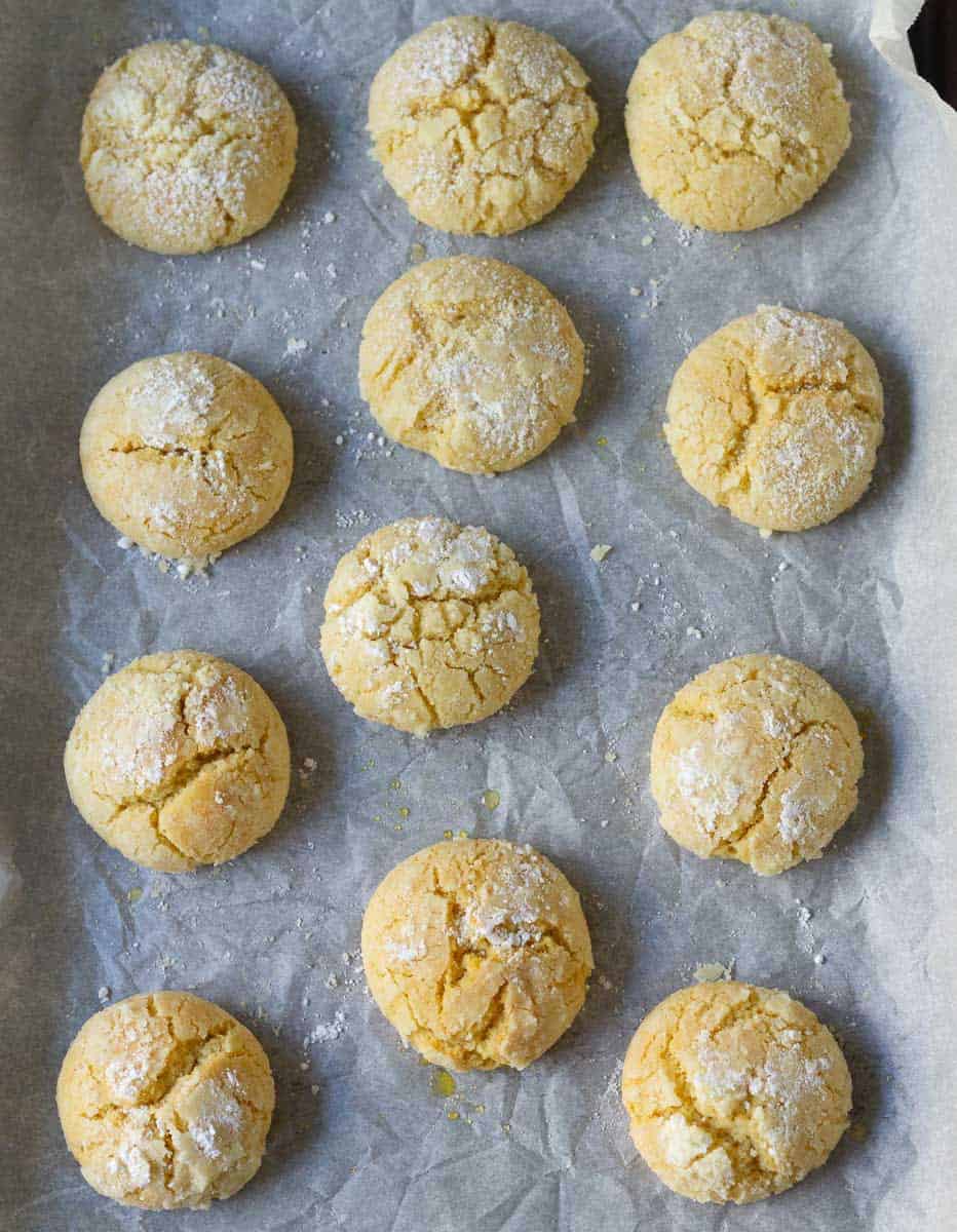 Baked lemon crinkle cookies on parchment paper.