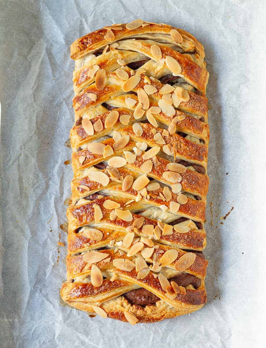 Baked puff pastry with chocolate with almonds on top on parchment paper.