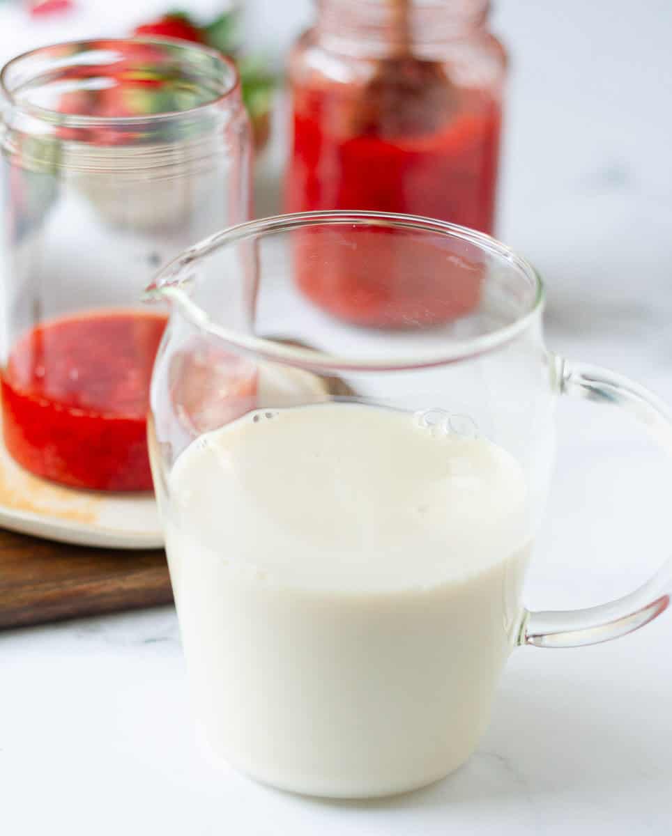 Milk for the strawberry milk in a glass pitcher.