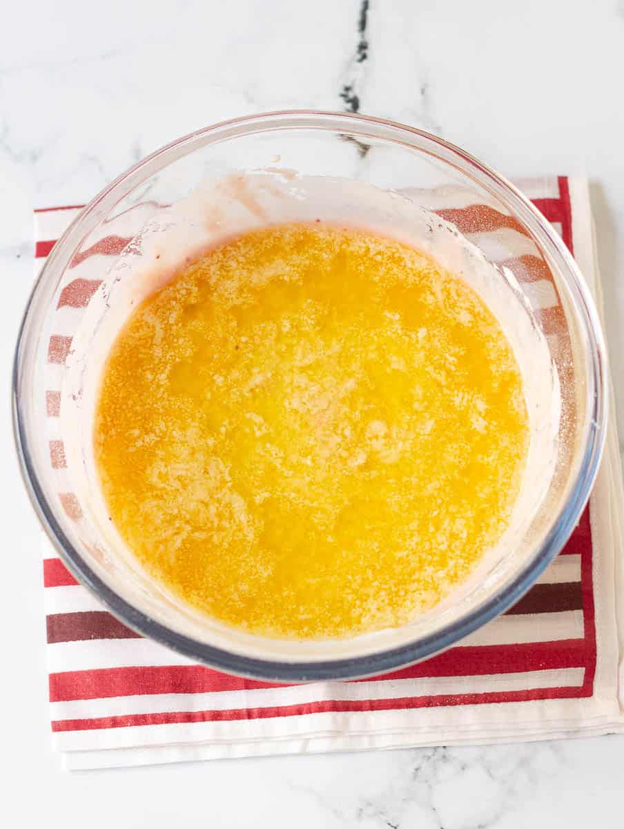 melted butter on top of the madeleine batter in a mixing bowl.
