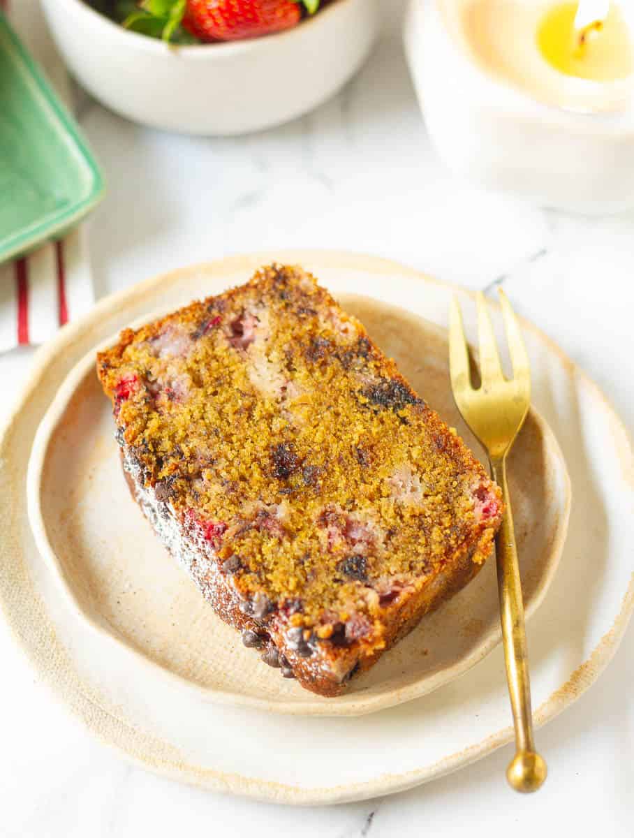 A slice of cake on a small plate with a golden fork on the side.