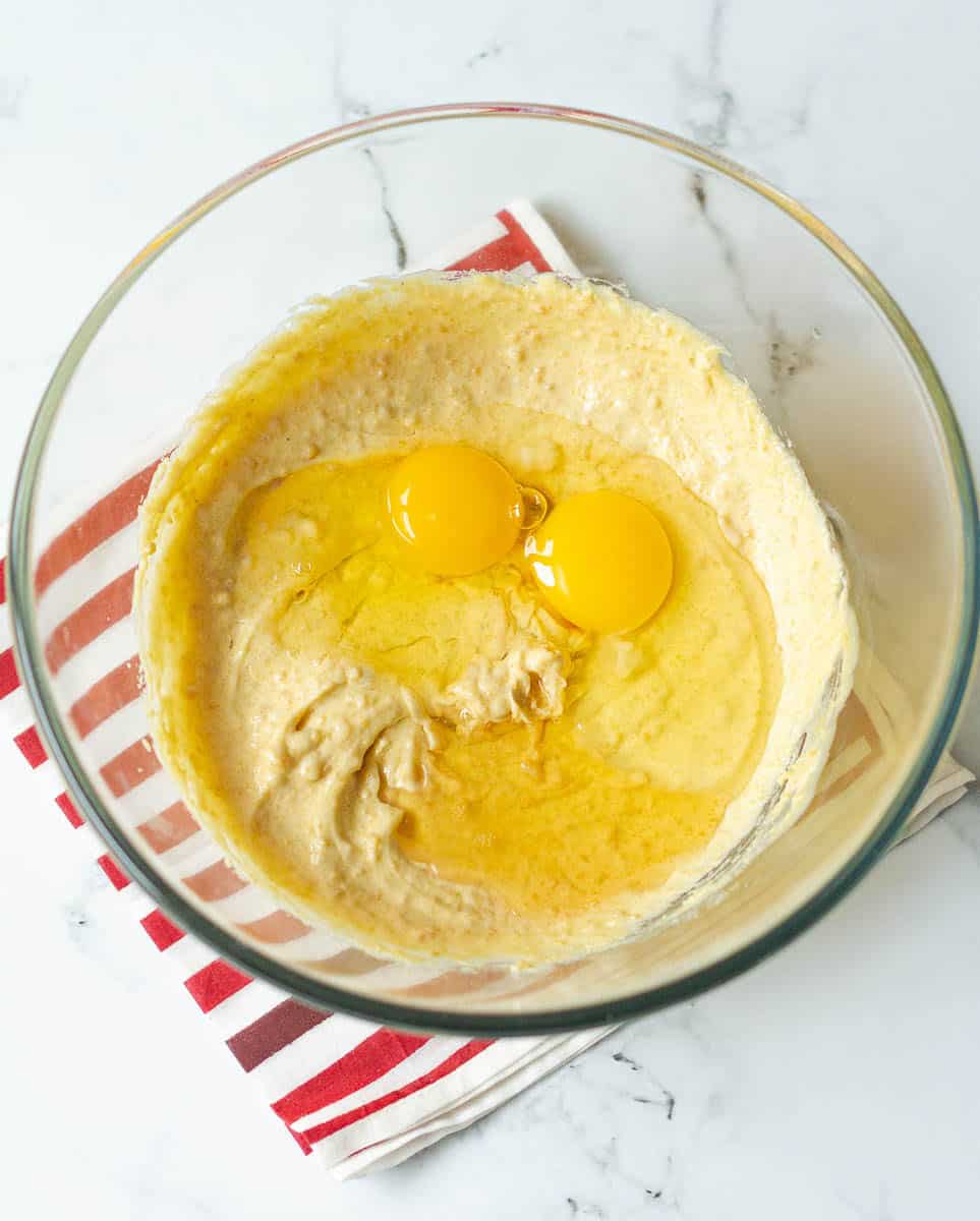 Eggs and vanilla extract in the mixture of butter and sugar in a glass bowl.