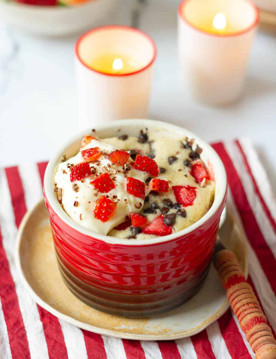 Strawberry Mug Cake topped with mascarpone cheese frosting and chocolate shavings.