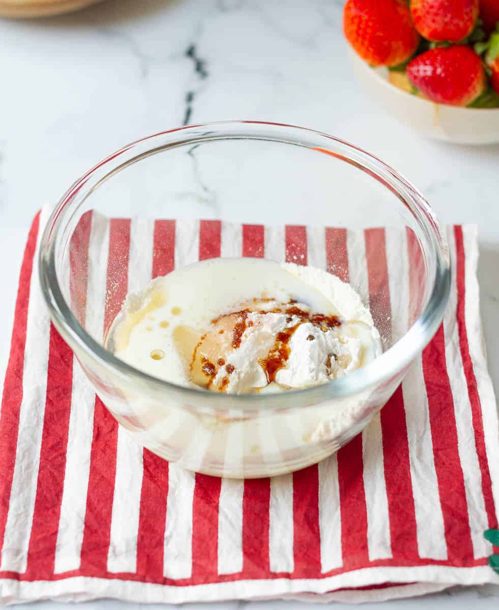 All cake ingredients in a small bowl on a red striped napkin.